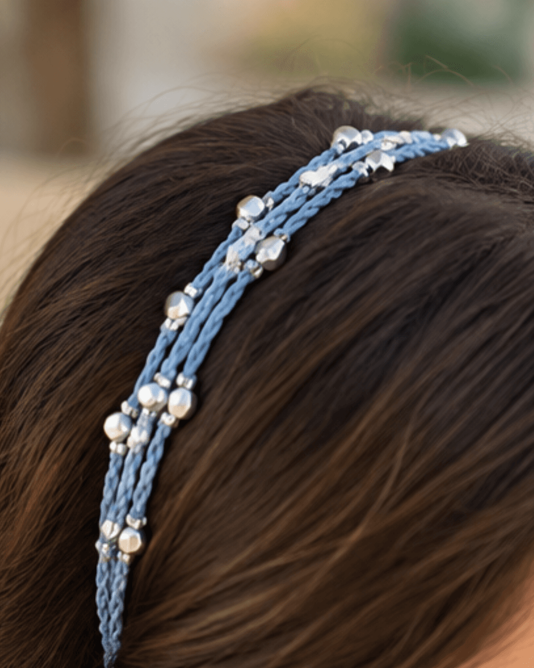 A blue crochet hairband with silver beads, worn in the hair