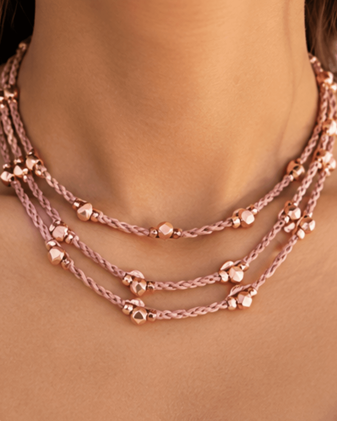 A layered pink crochet necklace with rose-gold beads